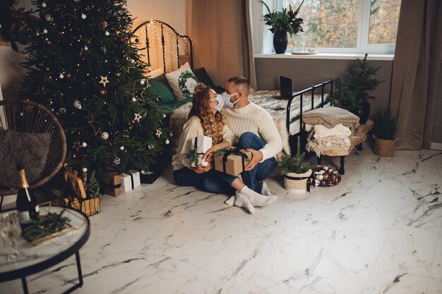 Pareja besándose en mascarillas con regalos.