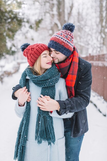 Pareja besándose en la nieve que cae