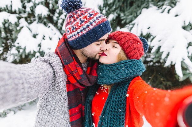 Pareja besándose para selfie en bosque