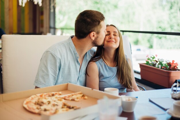 Foto gratuita pareja besándose sentado en pizzería