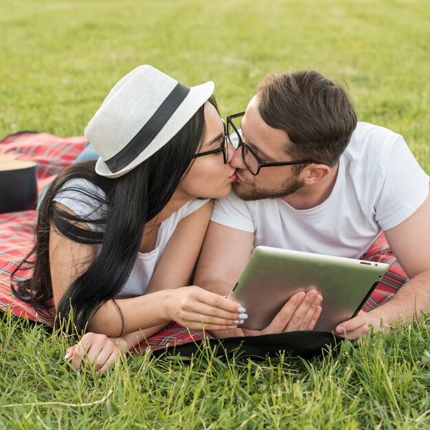 Pareja besándose sobre manta de picnic