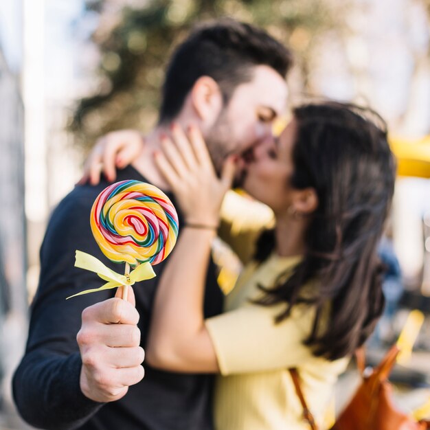 Pareja besándose sosteniendo a lollipop