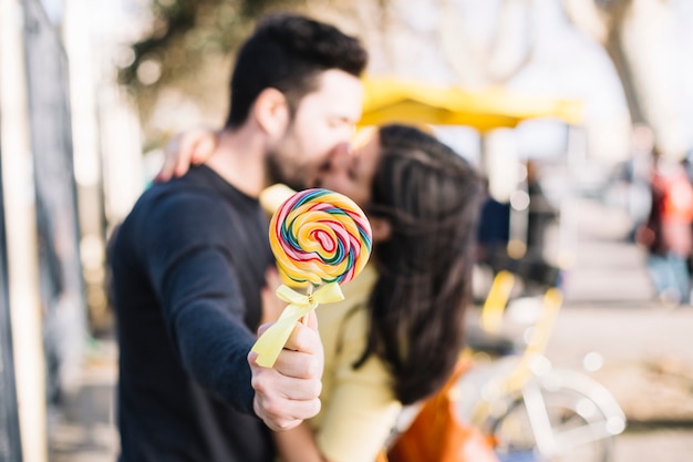 Pareja besándose sosteniendo a lollipop