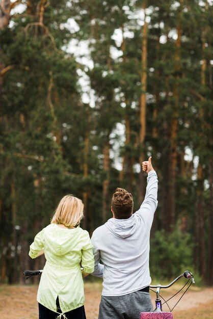 Pareja con bicicletas con fondo de bosque