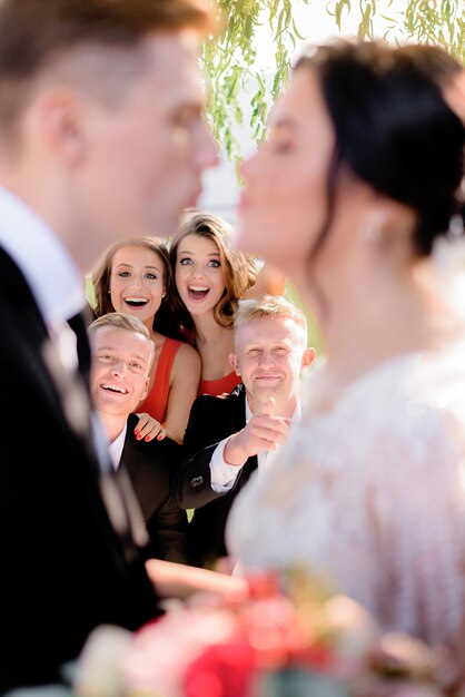 Pareja de boda borrosa con felices invitados sonrientes en el fondo afuera