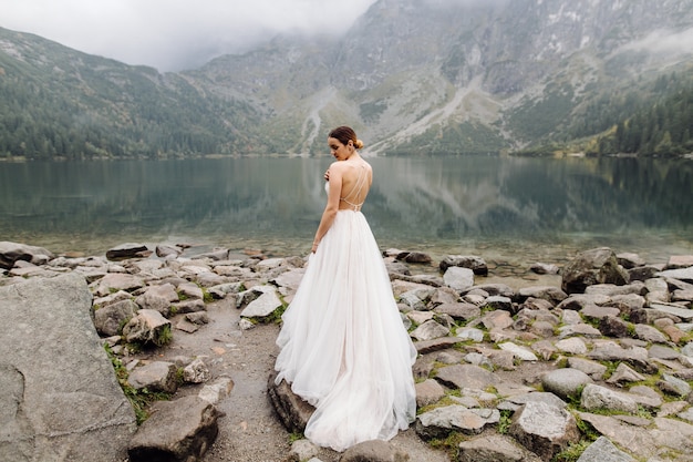 Pareja de boda romántica en pie de amor del lago Sea Eye en Polonia. Montes Tatra.