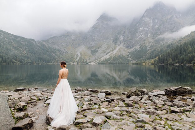 Pareja de boda romántica en pie de amor del lago Sea Eye en Polonia. Montes Tatra.