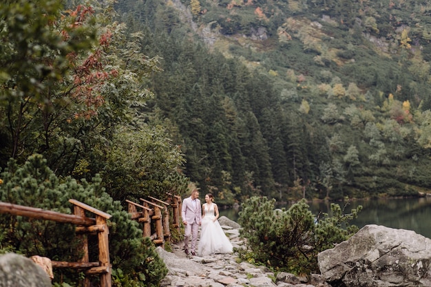 Pareja de boda romántica en pie de amor del lago Sea Eye en Polonia. Montes Tatra.