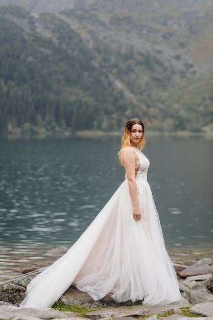 Pareja de boda romántica en pie de amor del lago Sea Eye en Polonia. Montes Tatra.