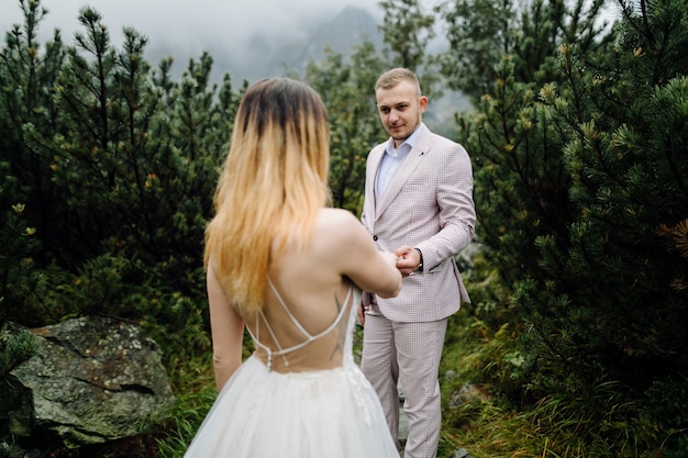 Pareja de boda romántica en pie de amor del lago Sea Eye en Polonia. Montes Tatra.