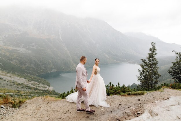 Pareja de boda romántica en pie de amor del lago Sea Eye en Polonia. Montes Tatra.