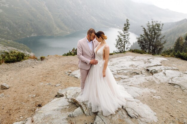 Pareja de boda romántica en pie de amor del lago Sea Eye en Polonia. Montes Tatra.