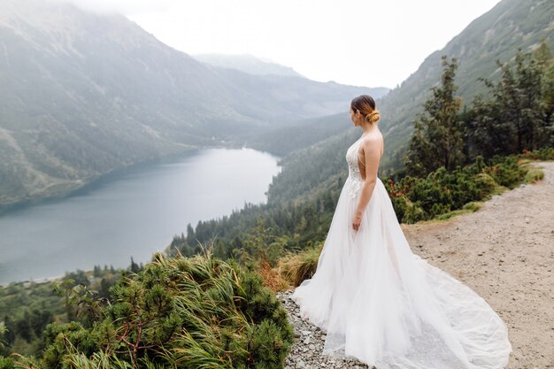 Pareja de boda romántica en pie de amor del lago Sea Eye en Polonia. Montes Tatra.