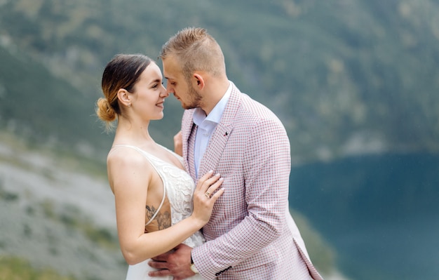 Pareja de boda romántica en pie de amor del lago Sea Eye en Polonia. Montes Tatra.