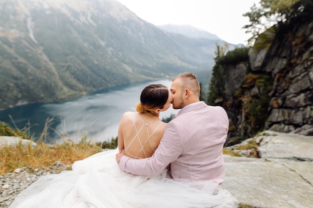 Pareja de boda romántica en pie de amor del lago Sea Eye en Polonia. Montes Tatra.