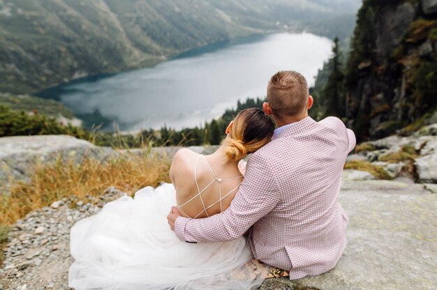 Pareja de boda romántica en pie de amor del lago Sea Eye en Polonia. Montes Tatra.