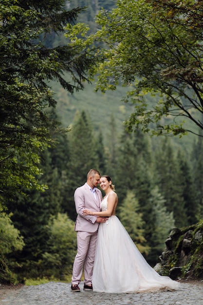 Pareja de boda romántica en pie de amor del lago Sea Eye en Polonia. Montes Tatra.