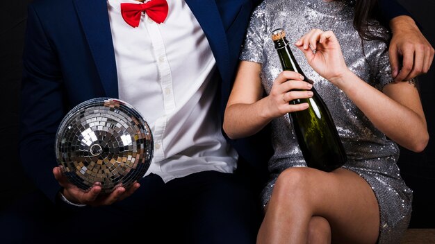 Pareja con bola de discoteca y botella de champagne