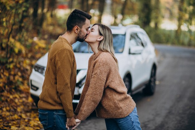 Pareja en el bosque besándose delante de un coche