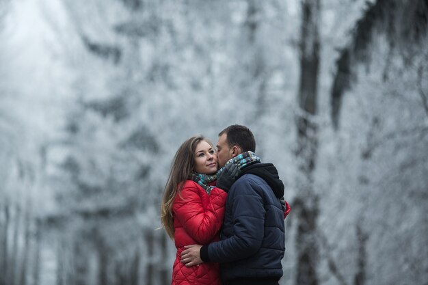 Pareja en bosque de invierno cerca del lago