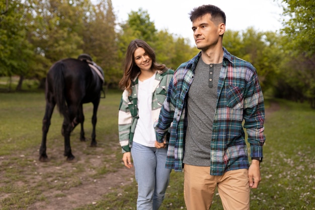 Foto gratuita pareja y caballo fuera de plano medio