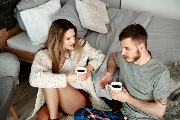 Pareja con café sentados en el suelo y hablando