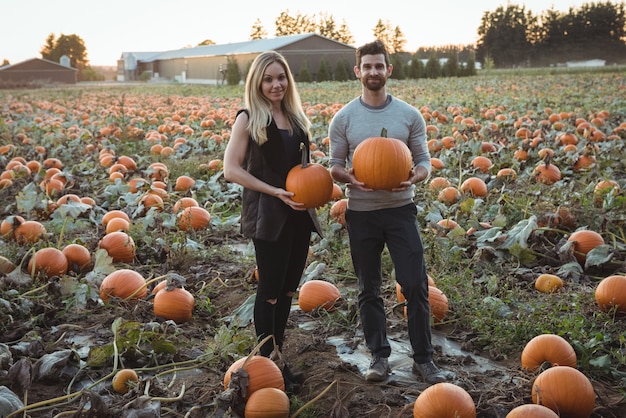 Foto gratuita pareja con calabaza en campo de calabaza