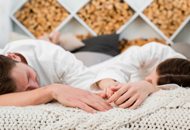 Pareja en la cama durmiendo mientras usa batas de baño