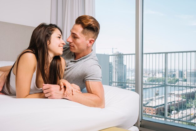 Pareja en la cama mirando amorosamente el uno al otro