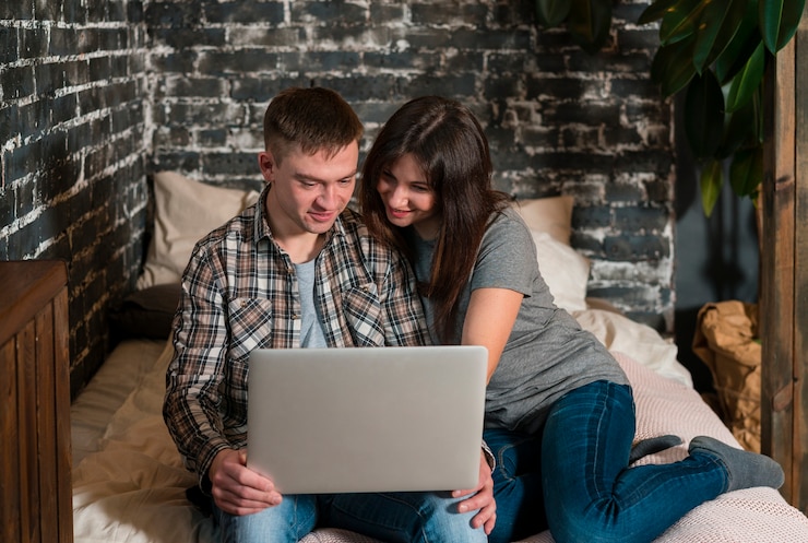 Foto gratuito pareja en la cama mirando portátil