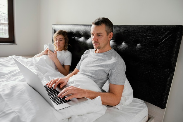 Foto gratuita pareja en la cama usando dispositivos