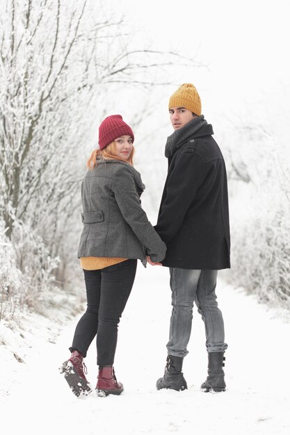 Pareja caminando al aire libre en invierno y mirando hacia atrás