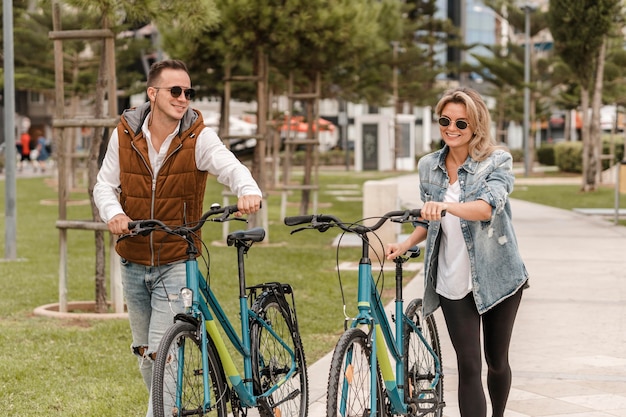 Pareja caminando con una bicicleta junto a ellos afuera