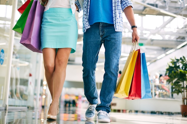 Pareja caminando por el centro comercial con bolsas de la compra