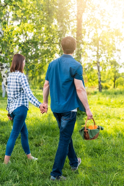 Pareja caminando con cesta de picnic en glade