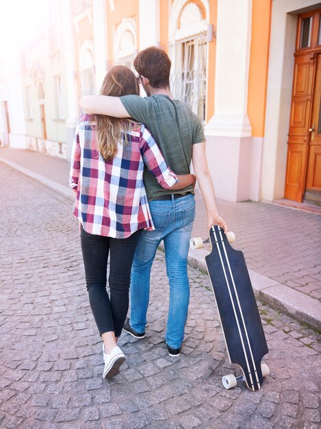 Pareja caminando por la ciudad. Cita romántica. Hombre patinador.