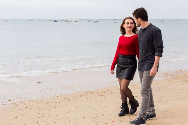 Pareja caminando y hablando en la orilla del mar