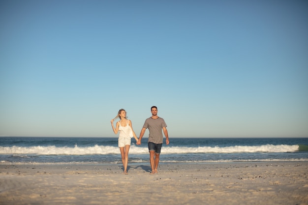 Pareja caminando juntos de la mano en la playa