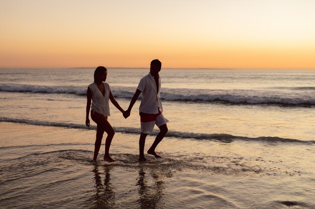 Pareja caminando de la mano en la playa