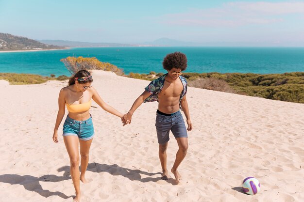 Pareja caminando en la playa y tomados de la mano