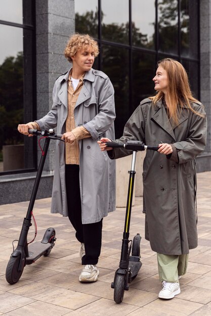 Pareja caminando con scooters eléctricos al aire libre