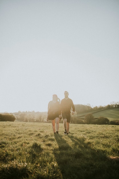 Pareja caminando y tomados de la mano al aire libre