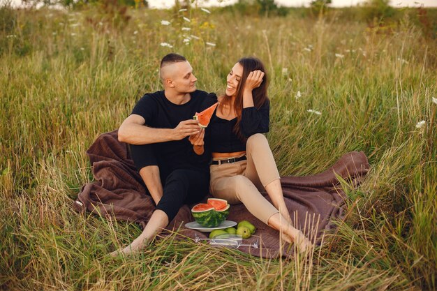 Pareja en un campo. Mujer con blusa negra. Personas con sandía.