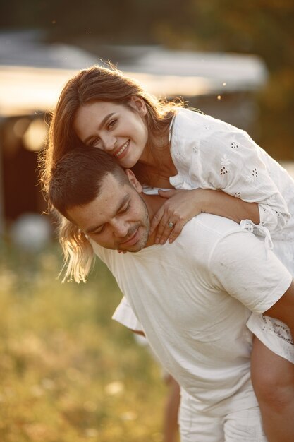 Pareja en un campo. Mujer con un vestido blanco. Fondo del atardecer.