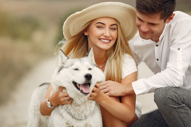 Pareja en un campo de otoño jugando con un perro