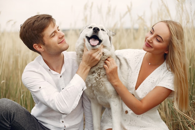 Pareja en un campo de otoño jugando con un perro