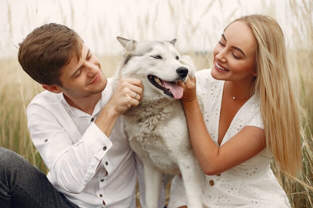 Pareja en un campo de otoño jugando con un perro