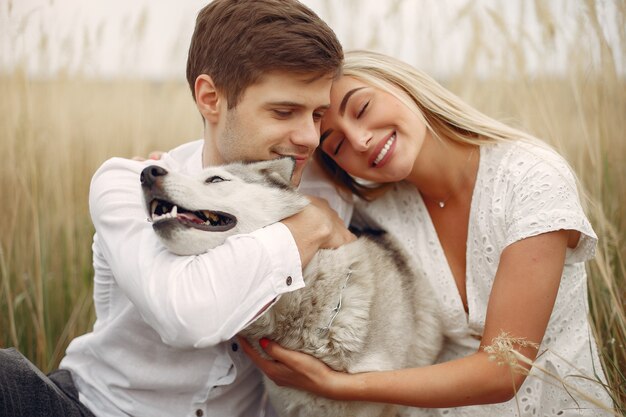 Pareja en un campo de otoño jugando con un perro