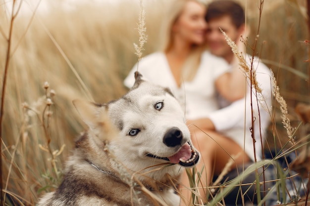 Pareja en un campo de otoño jugando con un perro