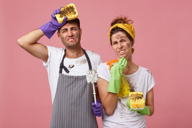 Pareja cansada y desordenada limpiando la casa